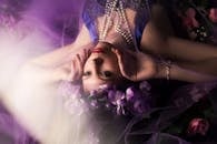 一幅被紫色花朵和柔和灯光环绕的女性艺术肖像