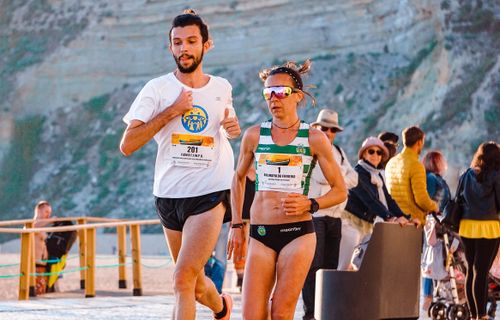 Free Two athletes running in a marathon with scenic background and spectators. Stock Photo