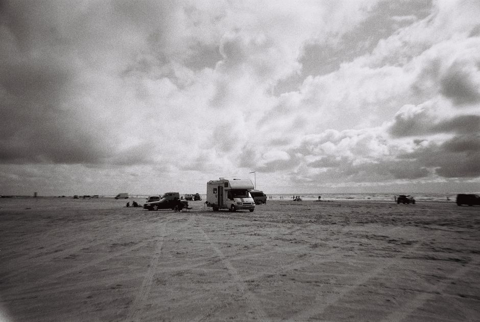 Camper van on a German beach during daylight, captured in black and white.
