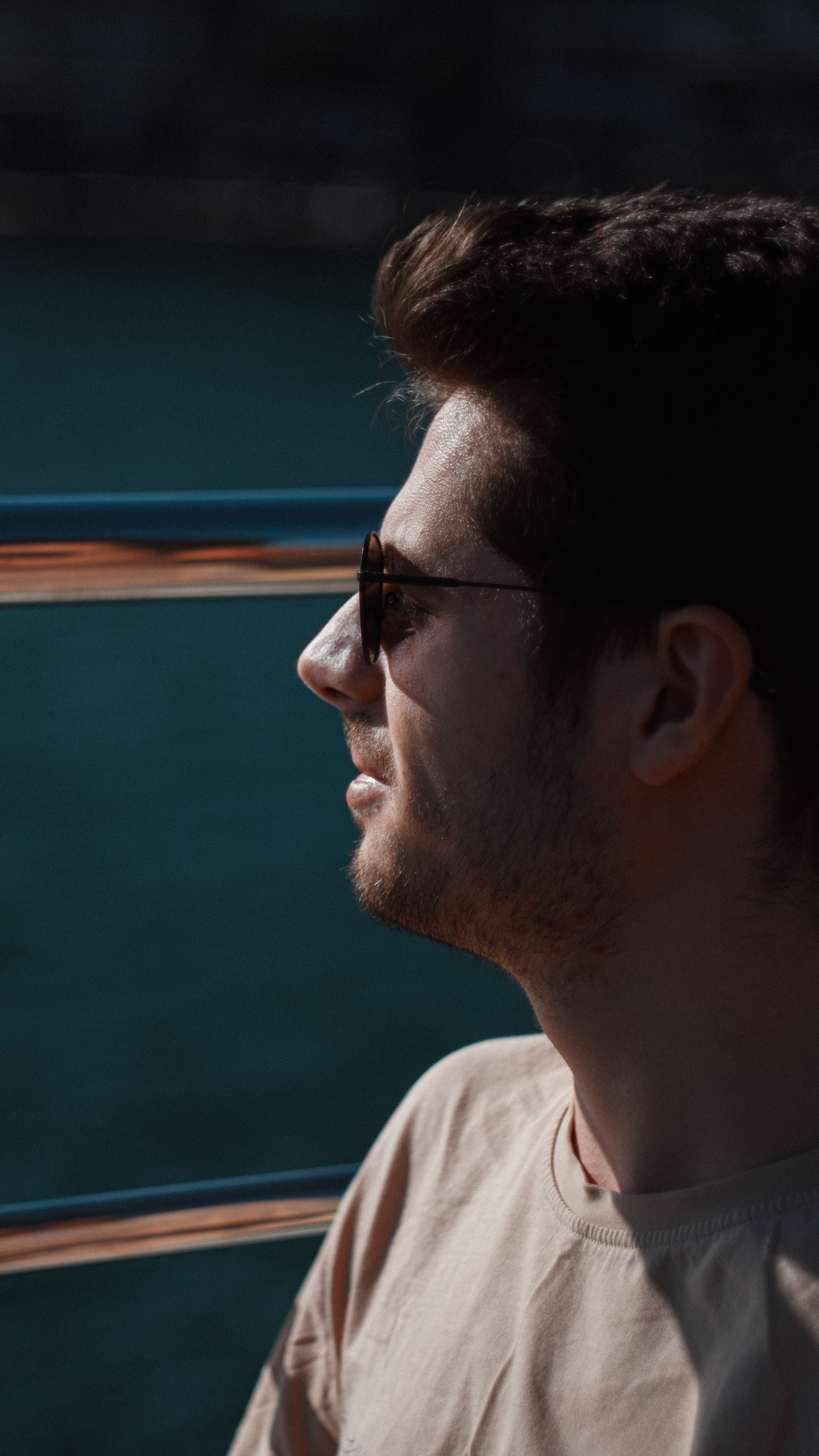Side profile portrait of a man with sunglasses, enjoying a sunny day outdoors.