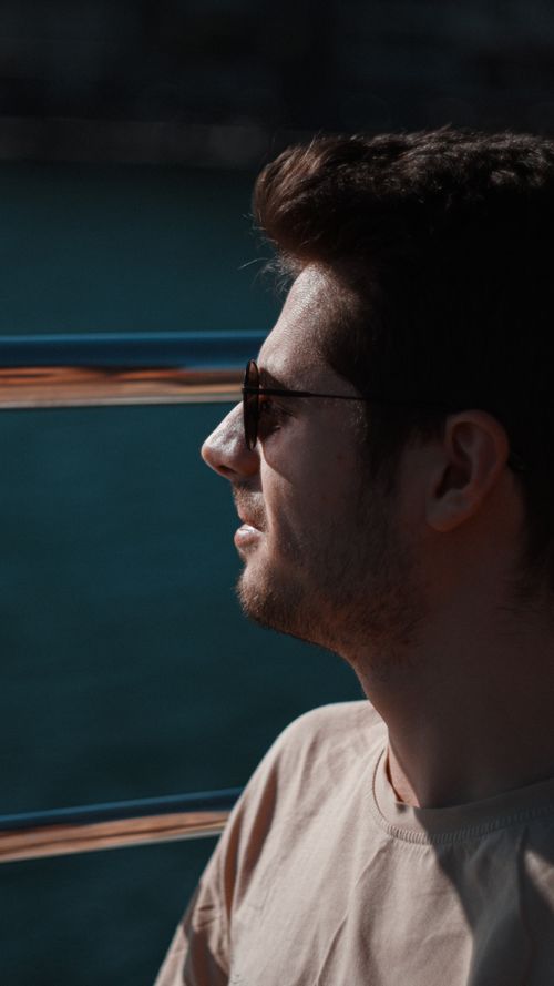 Free Side profile portrait of a man with sunglasses, enjoying a sunny day outdoors. Stock Photo