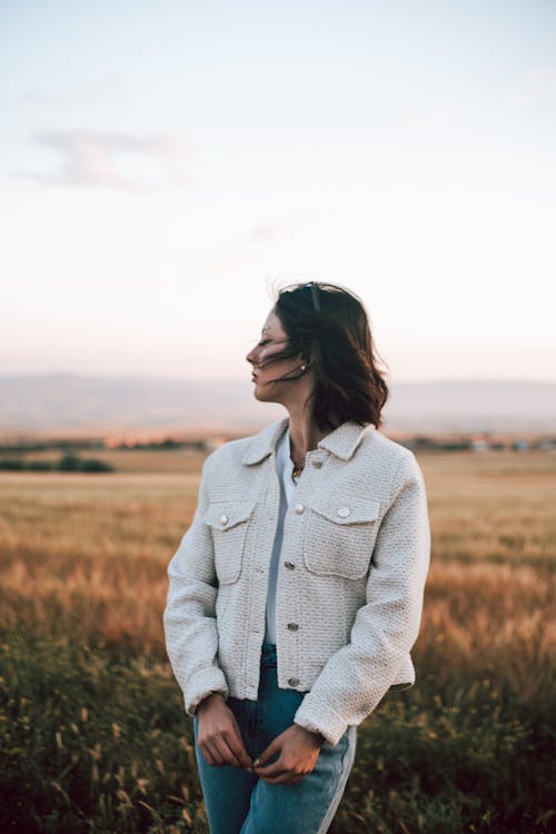 A woman standing in a field wearing a jacket