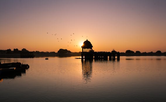 平静的湖面上，日落景色优美，映衬着寺庙的剪影和飞鸟