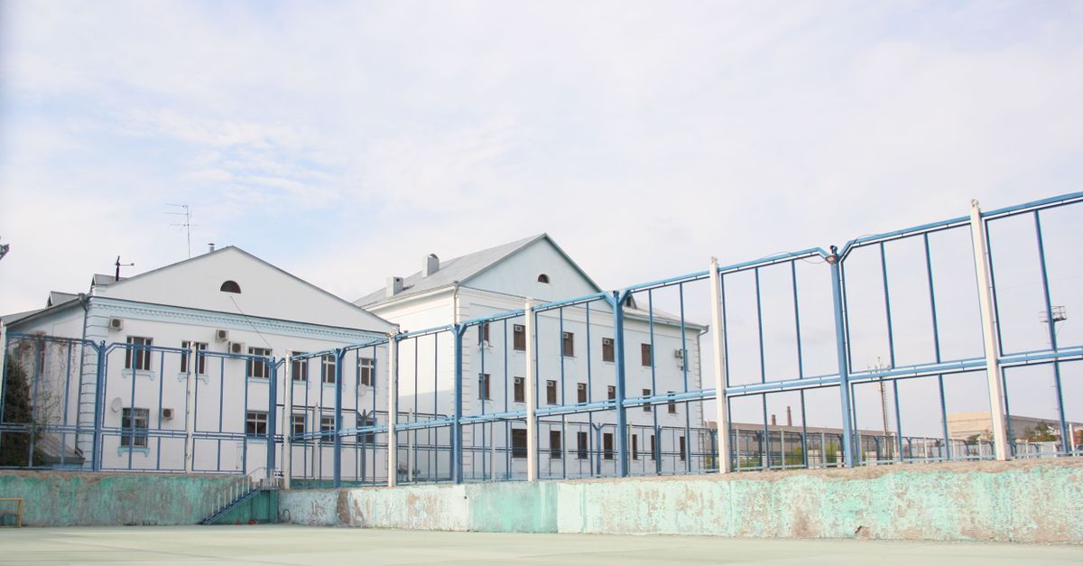 Modern building exterior with a metal fence and clear blue sky.