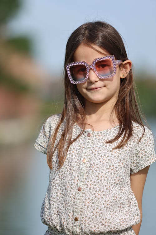 A little girl wearing sunglasses and a dress