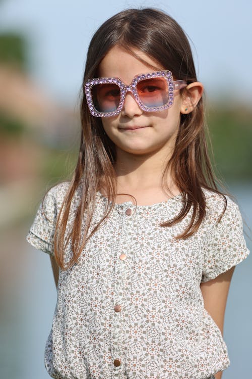 A little girl wearing sunglasses and a white shirt