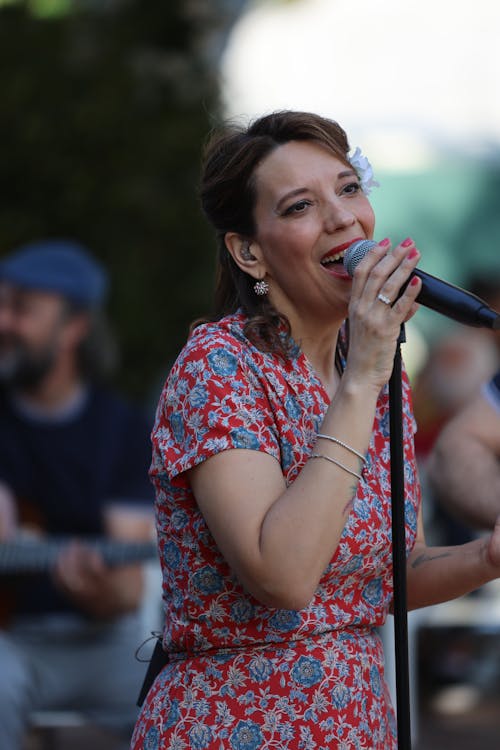 A woman in a floral dress singing into a microphone