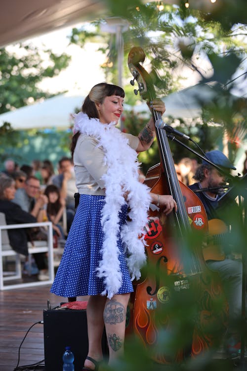A woman in a white dress playing a double bass