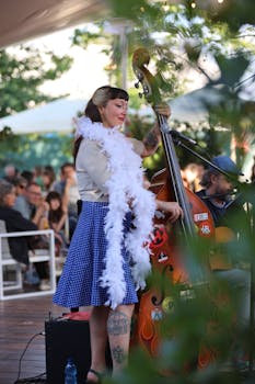 Woman performing with a double bass at an outdoor concert. Vibrant and energetic atmosphere.