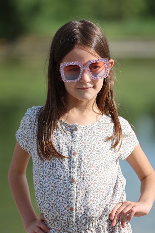 A little girl wearing sunglasses and a dress