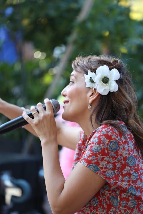 A woman with a flower in her hair singing into a microphone