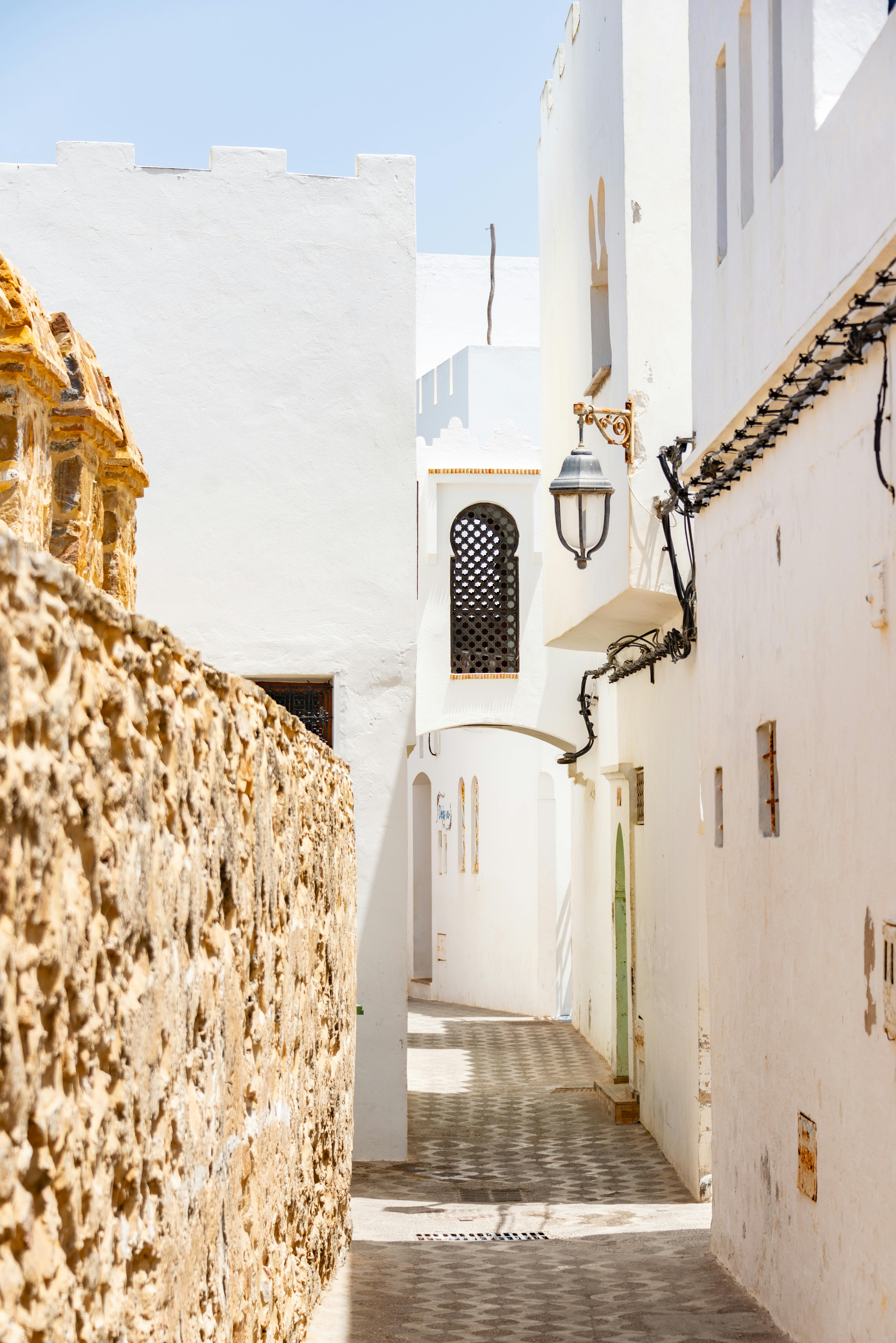 Explore the charm of a narrow street in a sunlit ancient city with traditional architecture.