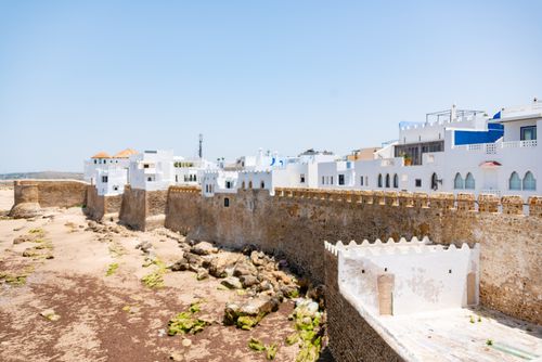 Free Explore the historic stone walls and whitewashed buildings of an ancient coastal city under a clear blue sky. Stock Photo