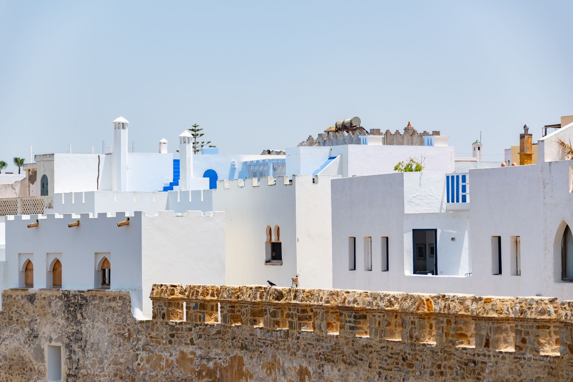 Charming view of traditional white and blue buildings under clear skies in Asilah, Morocco.
