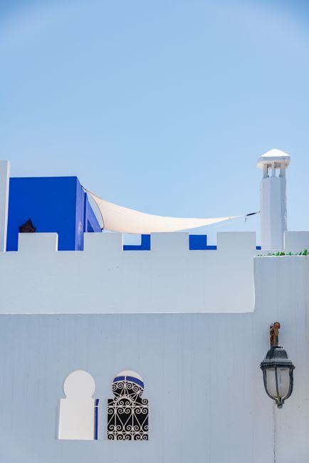Minimalist shot of white and blue Mediterranean architecture with clear blue sky.