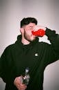 Man in Champion Hoodie Drinking from Red Cup