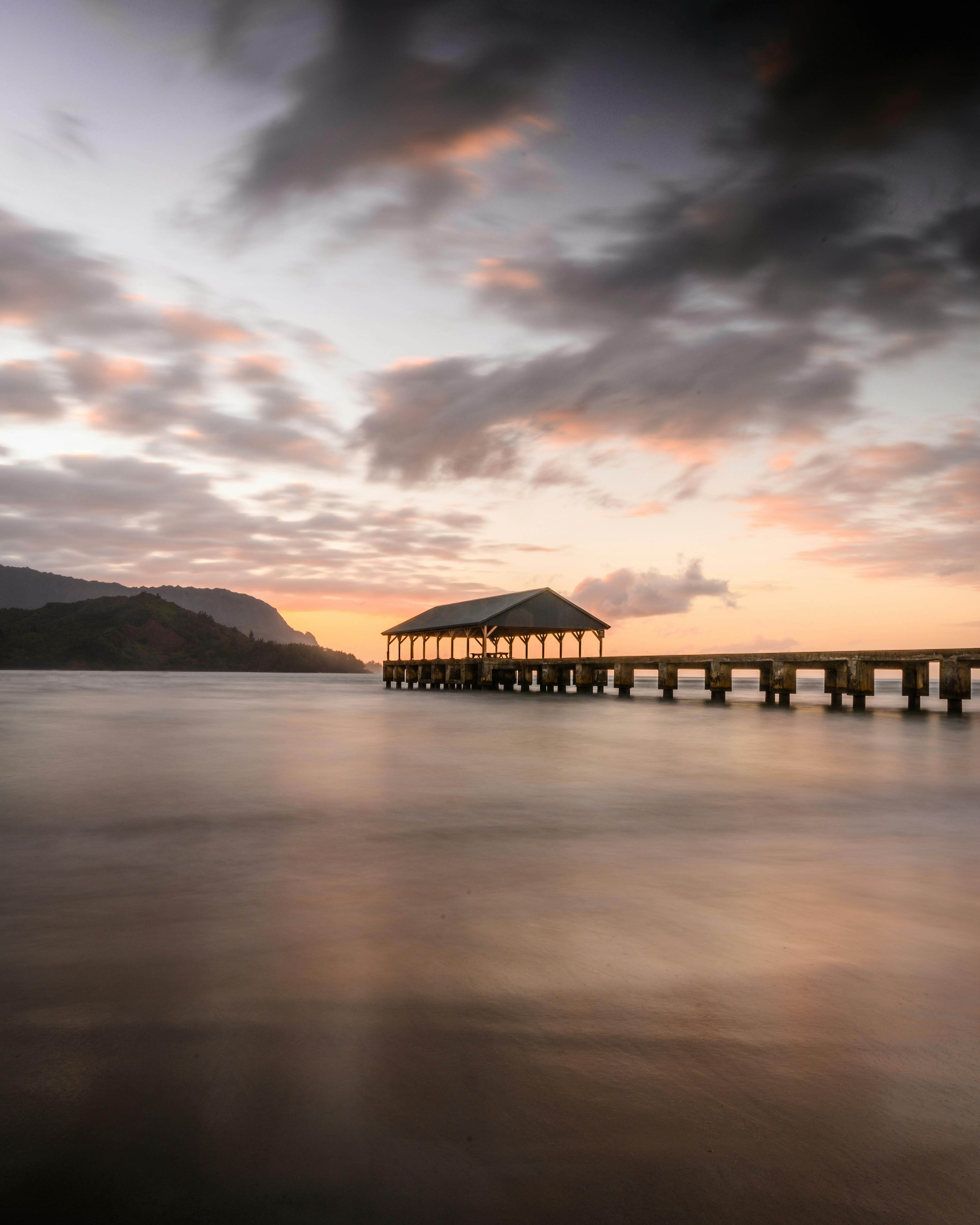 日落时分，夏威夷哈纳雷湾码头的宁静景色，展现了平静的海洋与天空