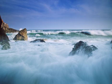 Captivating view of ocean waves crashing on a rocky shore with a dramatic sky overhead.