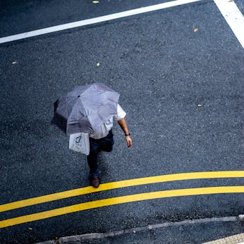 雨天，一名行人撑着伞，孤独地穿过街道