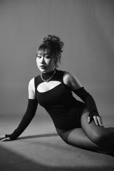 Striking black and white portrait of an Asian woman in a chic outfit, exuding elegance.