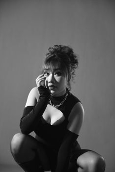 Elegant monochrome portrait of a model in a studio setting, showcasing fashion and style.