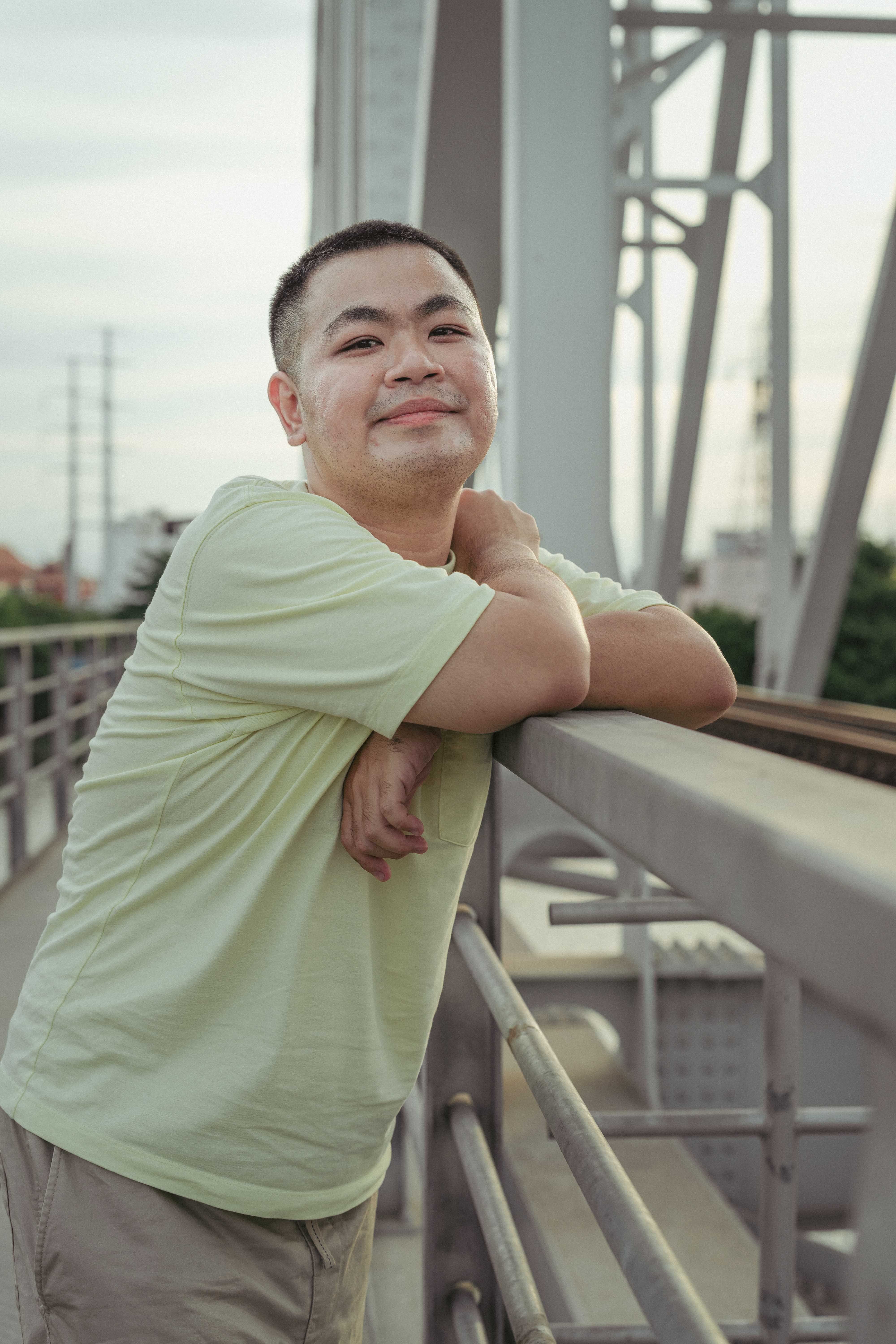 Man Smiling Leaning against Steel Bridge Railing · Free Stock Photo