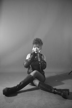 Black and white portrait of a woman in a stylish outfit with boots and gloves.