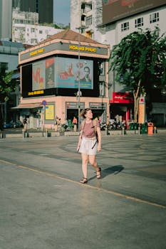 A woman casually walking along a street in Ho Chi Minh City during the day.