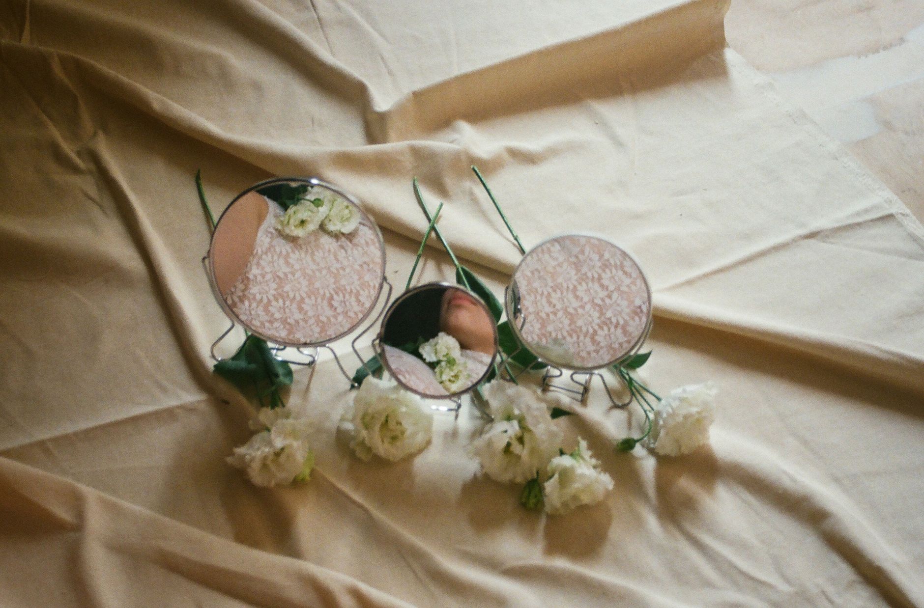Elegant composition of flowers with mirrors reflecting floral elements on fabric.
