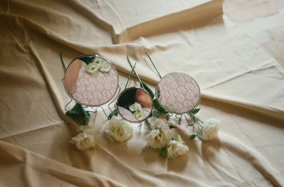 Elegant composition of flowers with mirrors reflecting floral elements on fabric.