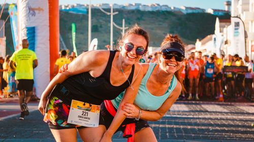 Free Two women laughing and posing during a sunny marathon, showcasing friendship and energy. Stock Photo
