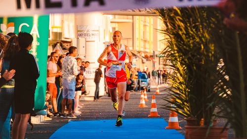 Free Athlete crossing finish line in outdoor marathon event with cheering crowd. Stock Photo