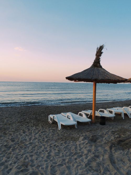 Free Peaceful Romanian beach with sun loungers and straw umbrellas at sunrise. Stock Photo