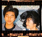 在电影画面中，一对年轻夫妇带着嬉戏的表情躺在创意背景前