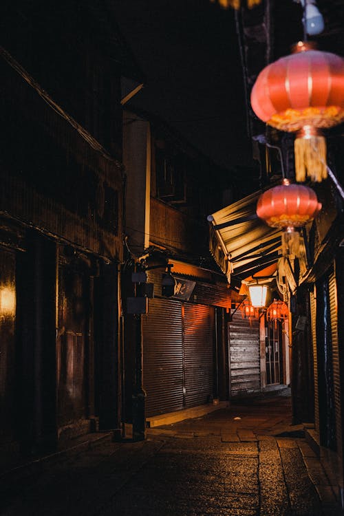 A street with lanterns and a dark alley