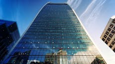 低角度拍摄的现代摩天大楼，其反光玻璃立面映照着城市天际线