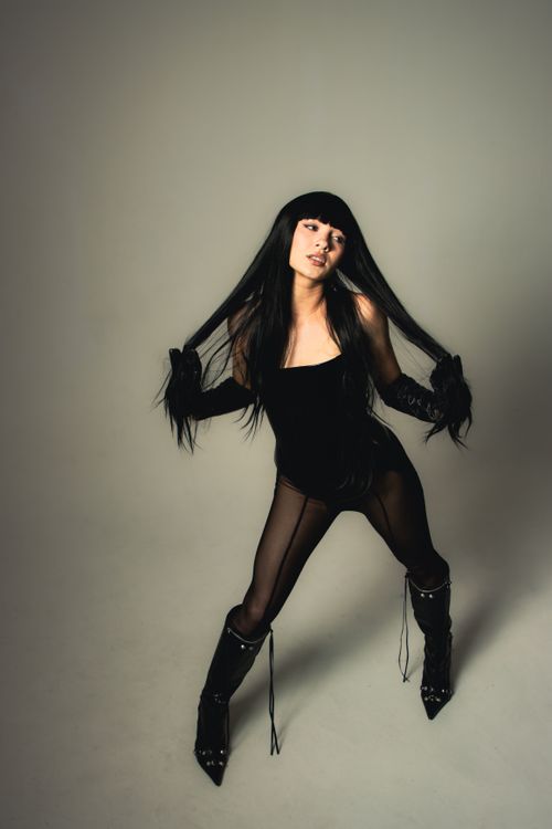 Free Elegant woman in black outfit and high heel boots posing confidently in a studio setting. Stock Photo