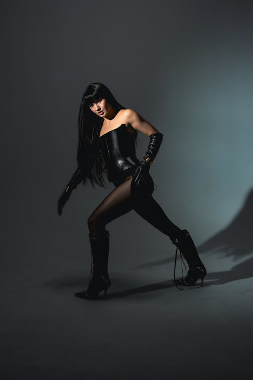 A woman in black leather posing in the dark