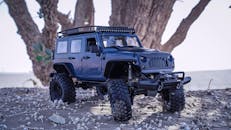 日光下，一辆停在沙地上、背景有树的微型越野玩具汽车被拍摄于户外