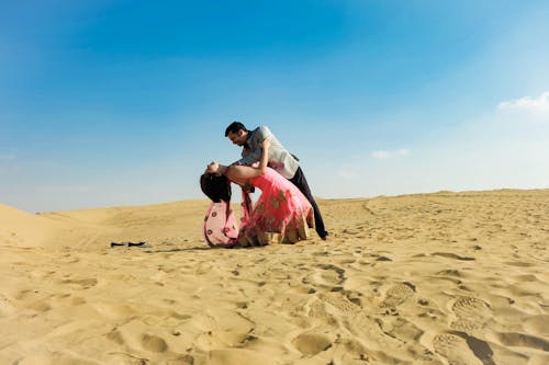 Photo of a Man and Woman Dancing on Desert