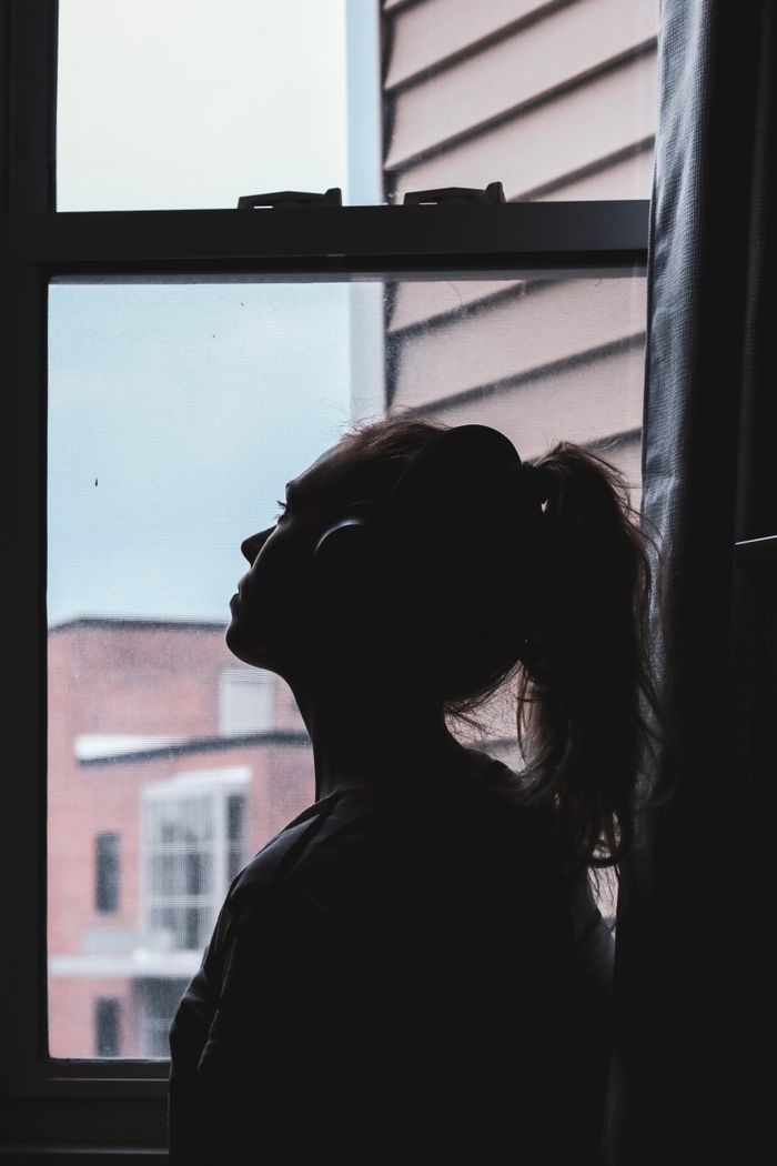 Silhouette of a person gazing out a window — contemplation and enquiry