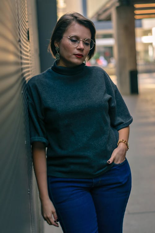 Photo of a Woman in Turtleneck Shirt Leaning on Wall