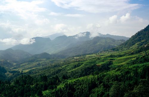 Free A scenic view of green hills and mountains under a bright sky, perfect for travel inspiration. Stock Photo