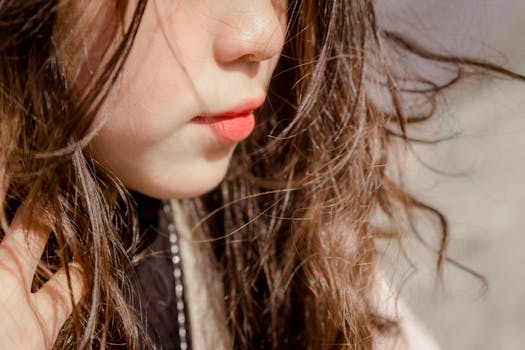 A detailed close-up of a woman with flowing hair and natural beauty, showcasing vibrant lips and skin.