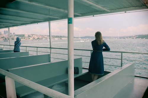 A woman is standing on a boat looking out at the water