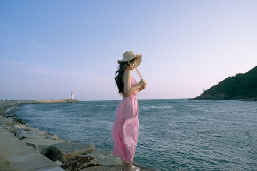 A woman in a pink dress standing on a pier