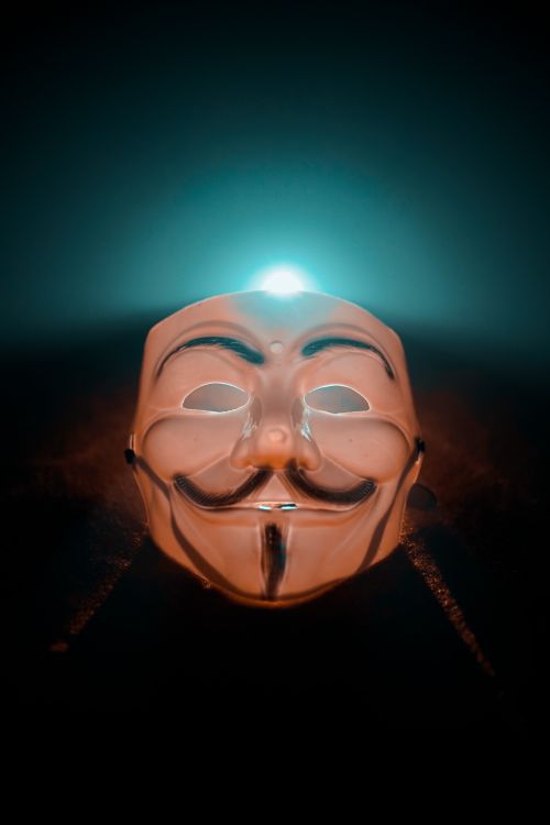 Free A compelling photo of an illuminated Anonymous mask against a dark background, taken in Jaipur, India. Stock Photo