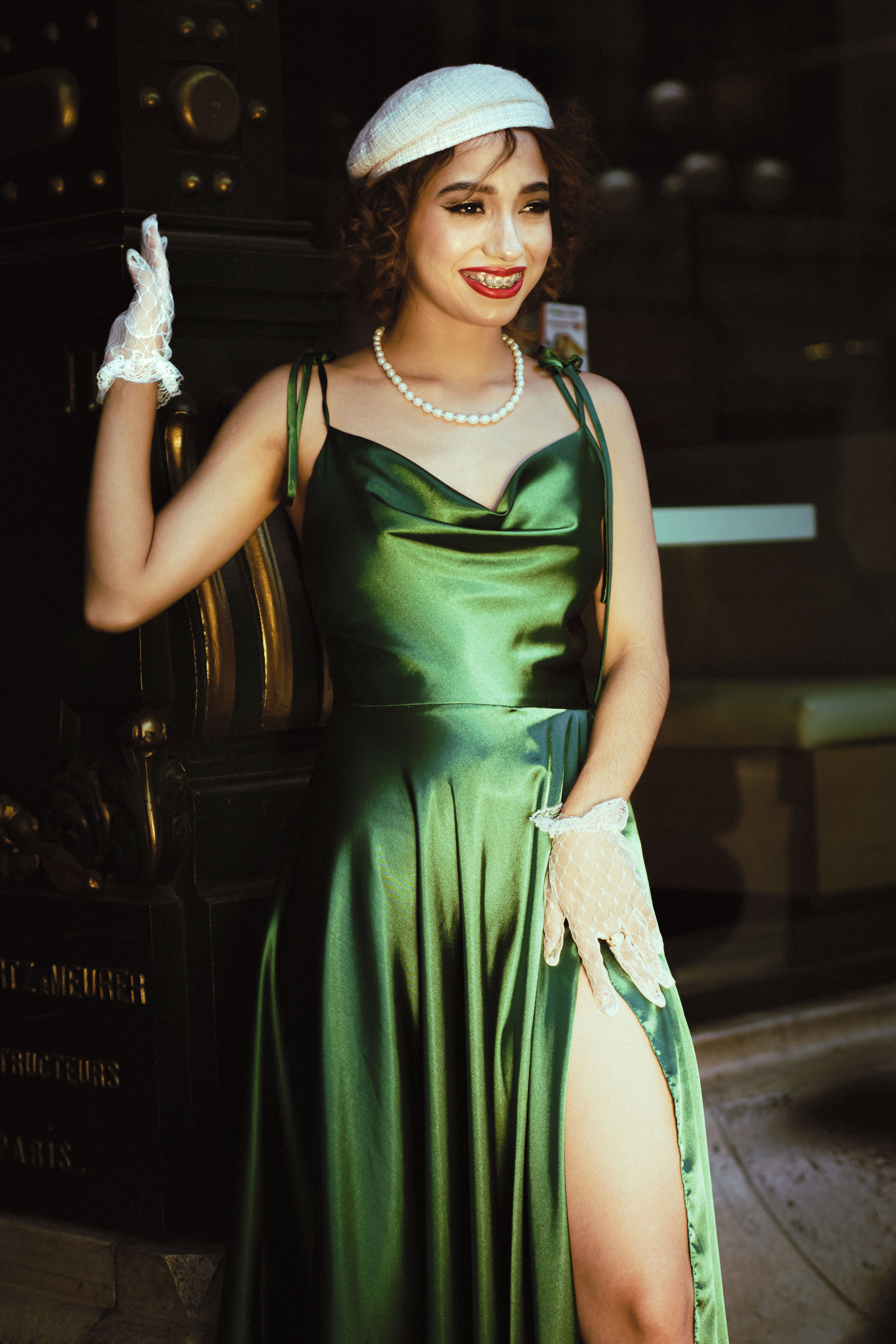 Elegant woman in green satin dress, vintage style, smiles in Puebla's historic setting.