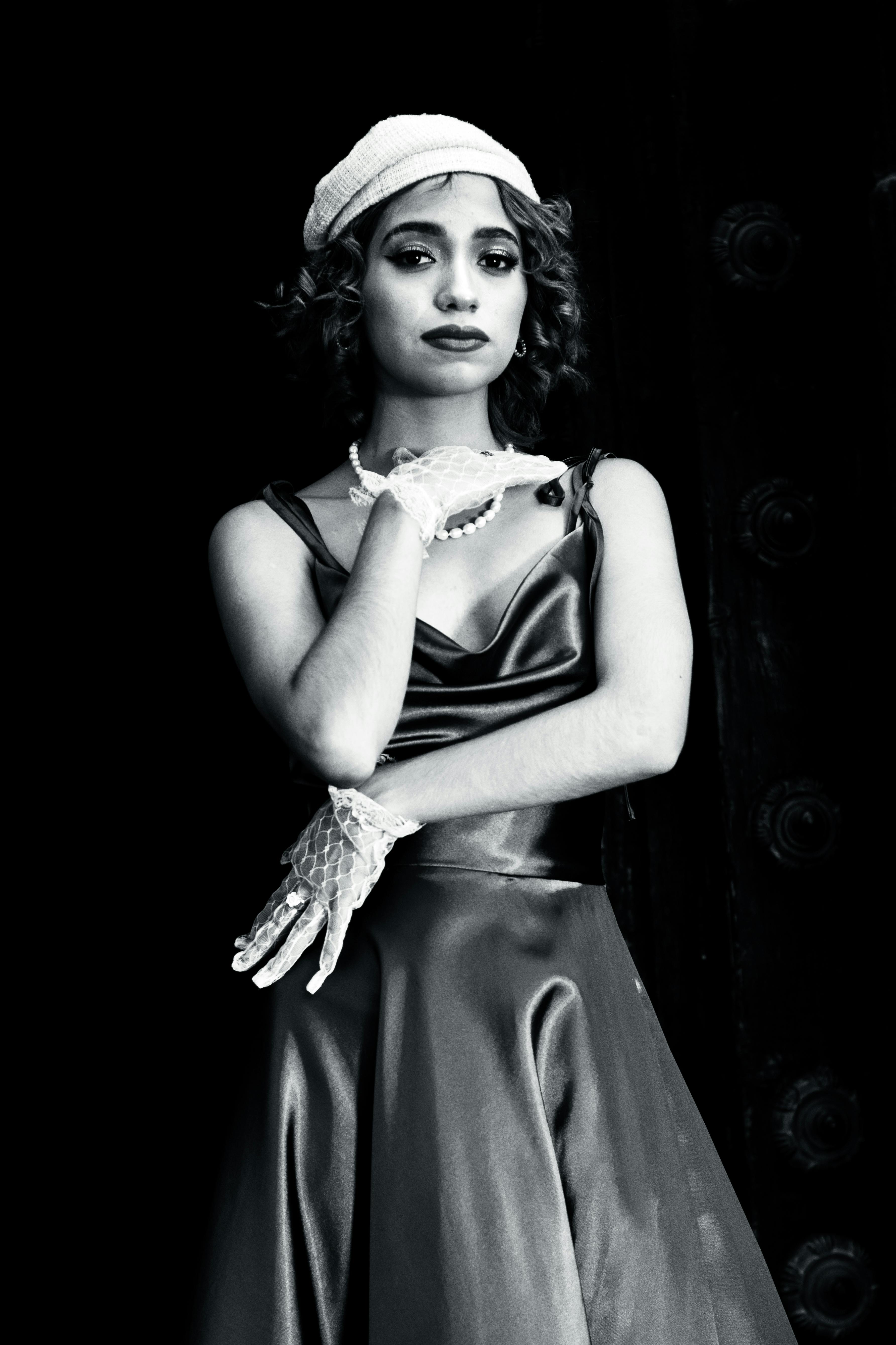Classic black and white portrait of a woman in elegant retro fashion with hat and gloves.