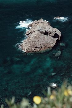 Aerial view of rugged rocks in turquoise Atlantic waters at Cabo da Roca, Portugal.